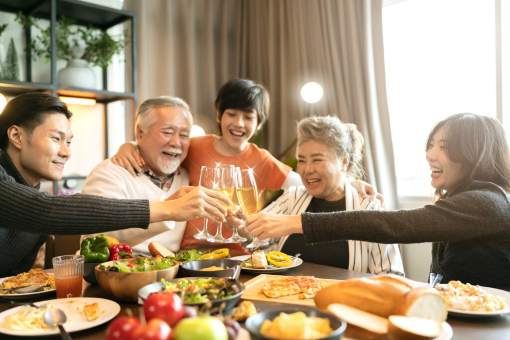 asian multi generation grandparent grandchild happiness joyful dinner together at home,holidays, celebration and people concept - happy friends with sparklers having christmas thanksgiving dinner
