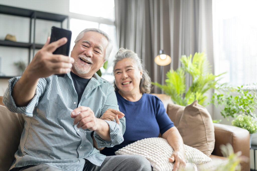 happiness asian old senior retired couple enjoy videocall to family together on sofa in living room at home,asian people use smartphone communication to family home isolation ides concept