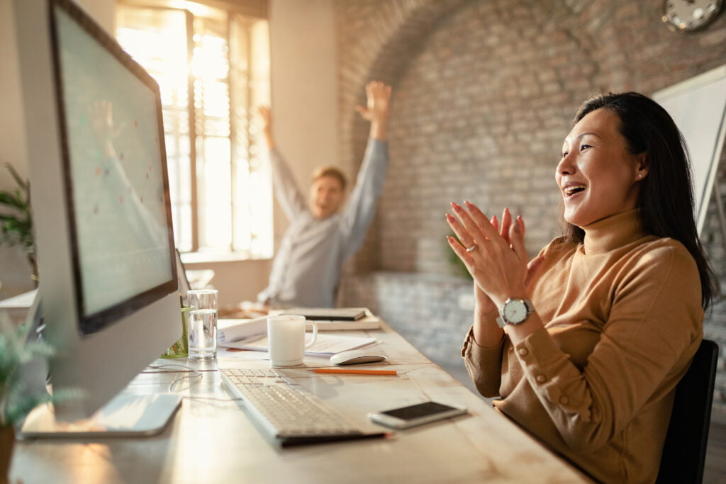 asian entrepreneur her coworker celebrating business success while using computer office