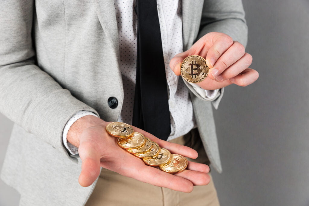 close up man holding stack golden bitcoins